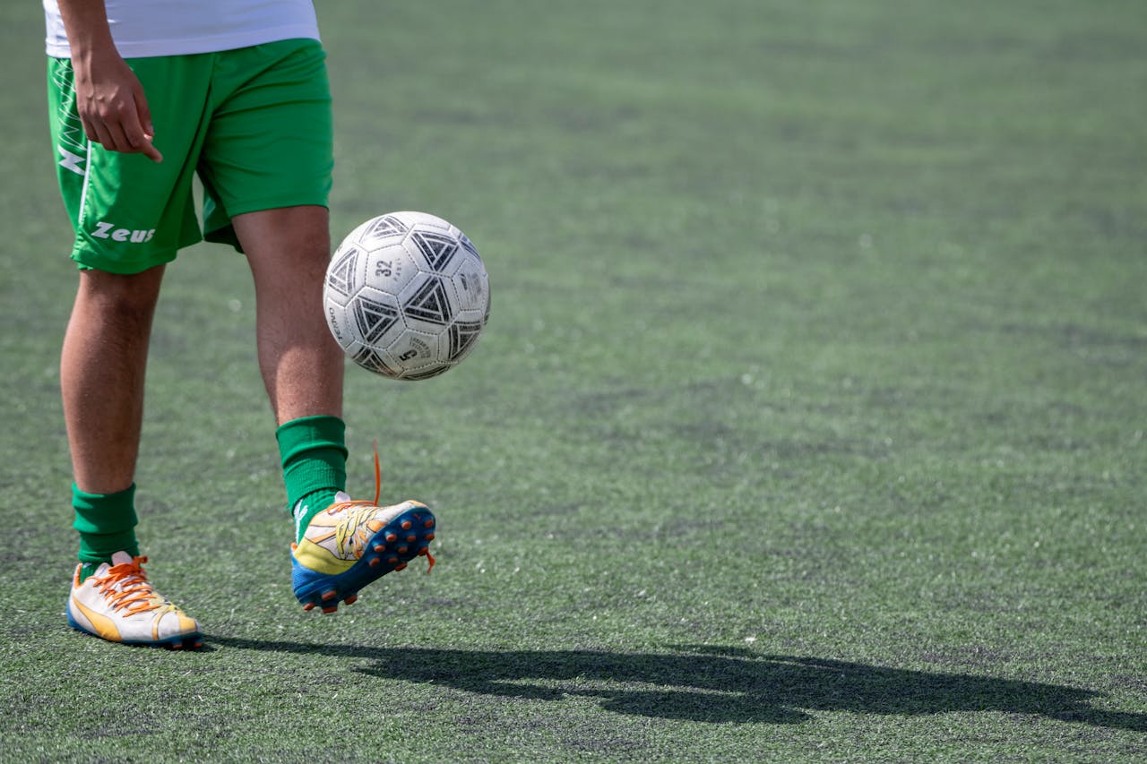 Football player practices juggling skills on a grass field. Action sports scene.